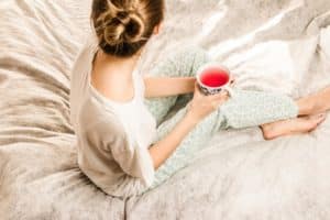 Woman sitting on the bed with a cup of tea