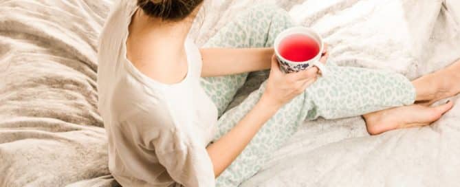 Woman sitting on the bed with a cup of tea