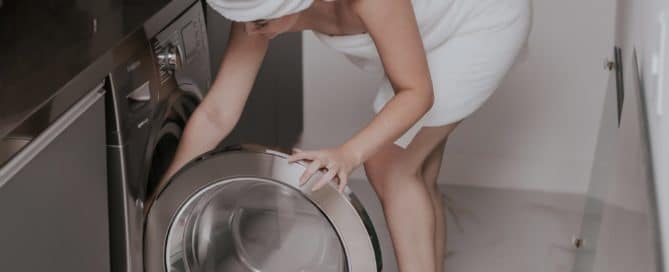 woman in bath towel reaching into a dryer